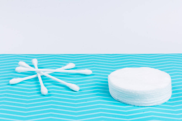 Cotton sponge or cotton cosmetic pad and ear sticks on blue background. Makeup removal and skin care concept. Closeup, top view - Photo, Image