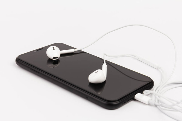 Навушники та телефон на білому тлі. Готовий слухати музику
 - Фото, зображення