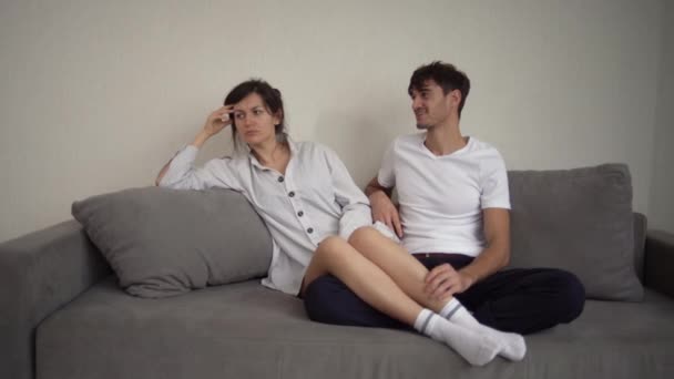Das Ehepaar sortiert und setzt sich auf das Sofa, die Mädchenbeine liegen auf dem Schoß der Jungs. Die Krise in der Beziehung der Liebenden. - Filmmaterial, Video