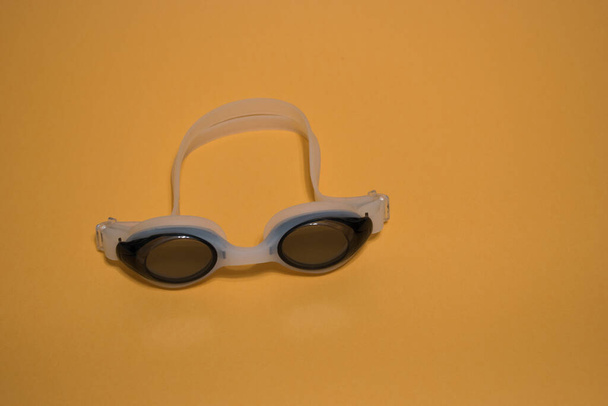 Gafas blancas profesionales para nadar aisladas sobre fondo amarillo.Gafas de natación blancas. - Foto, Imagen
