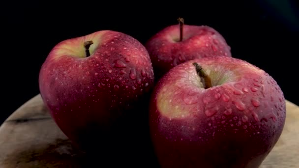 Estudio bodegón con tres manzanas rojas footage.Fresh manzanas rojas con gotas de agua en la superficie de madera table.black en contraste con un fondo gris oscuro. - Imágenes, Vídeo