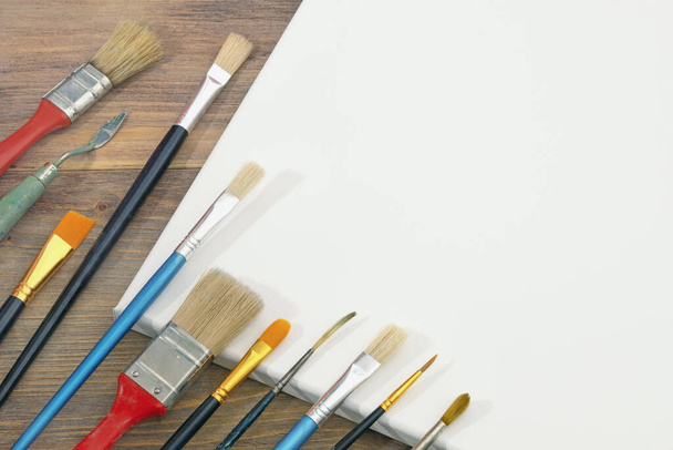 Different paintbrushes and white canvas. Free space for text or picture - Photo, Image