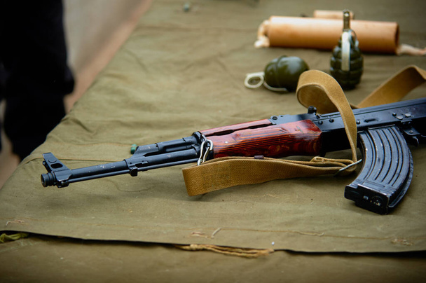 Un rifle de asalto Kalashnikov en la mesa junto con granadas de mano. - Foto, Imagen