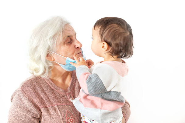 Vnučka se snaží dát své babičce masku z úst políbit - Fotografie, Obrázek