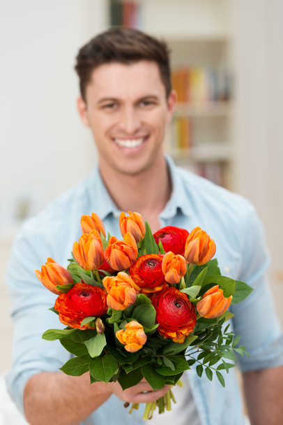Smiling man offering a bunch of fresh flowers - Zdjęcie, obraz