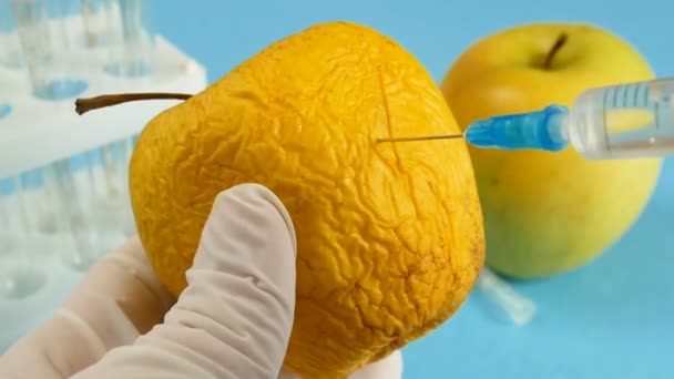 appel in genetische manipulatie laboratorium met spuit en reageerbuisjes op blauwe achtergrond, gmo food concept - Video