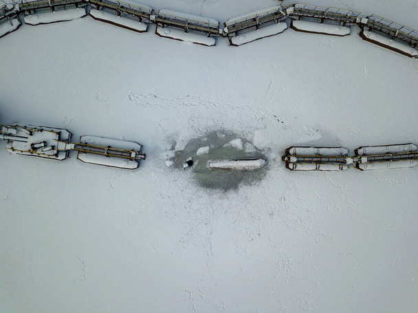 Pasarelas metálicas en un puerto industrial congelado. Vista aérea del dron. Día nevado de invierno. - Foto, imagen