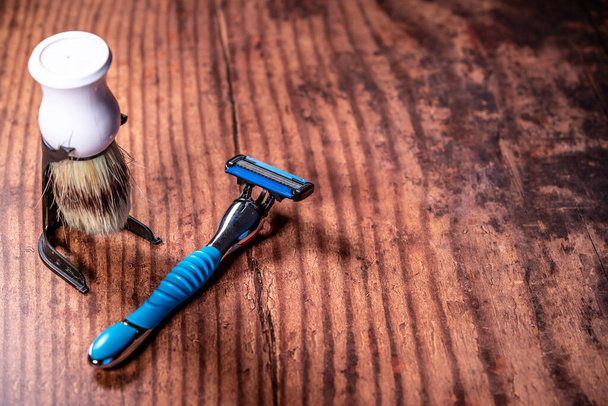 Un primer plano de una maquinilla de afeitar húmeda manual y un cepillo de afeitar en una mesa de madera - Foto, imagen
