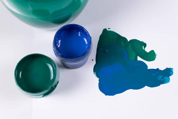 dva tahy a dvě sklenice zelené a modré gouache, na pozadí sklenice vody pro štětce - Fotografie, Obrázek