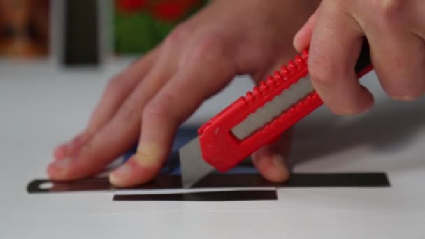 De mensenhanden knippen voorzichtig een kleine magneet uit met een mes. - Video