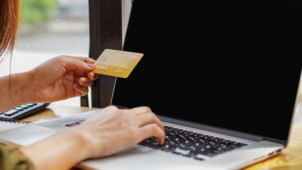 Кредитна картка в руці молодої жінки, яка платить електронні рахунки через ноутбук
 - Фото, зображення