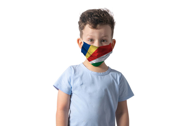 Αναπνευστήρας με σημαία Σεϋχελλών. Λευκό αγόρι βάζει ιατρική μάσκα προσώπου απομονώνονται σε λευκό φόντο. - Φωτογραφία, εικόνα