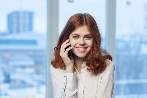 wesoła kobieta biznesu rozmawia przez okno w biurze telefonicznym w tle - Zdjęcie, obraz
