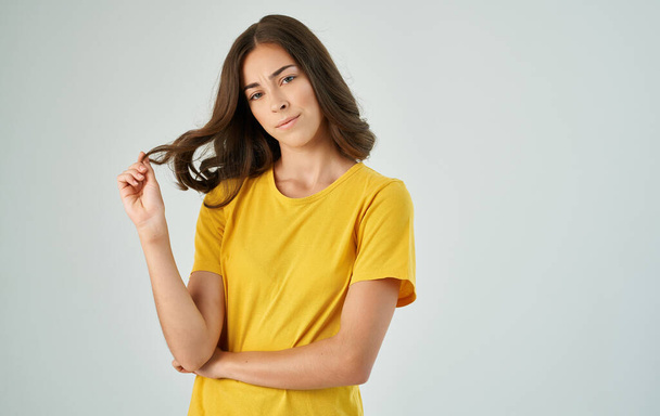 pretty brunette in a yellow t-shirt gray background smile emotions - Φωτογραφία, εικόνα