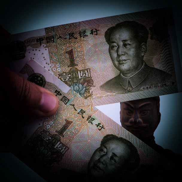 Da dietro le banconote in tagli di uno yuan cinese sbirciare fuori la testa di una statuetta copiando un soldato dall'antico famoso esercito di terracotta dell'imperatore Qin Shi Huang a Xi'an - Foto, immagini