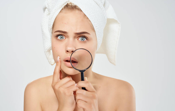 Frau mit Handtuch auf Kopf Lupe in der Hand nackte Schultern Kosmetologie Dermatologie - Foto, Bild