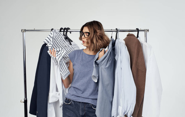 Donna emotiva si trova vicino a vestiti su un appendiabiti in uno spogliatoio su uno sfondo leggero shopping - Foto, immagini
