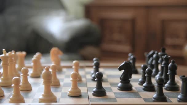 Ein Mann bewegt Schachfiguren auf einem Schachbrett. Vor dem Hintergrund alter Sachen. Chess.Player macht einen Zug, entwickelt Schachstrategie, spielt Brettspiel mit dem Gegner. - Filmmaterial, Video