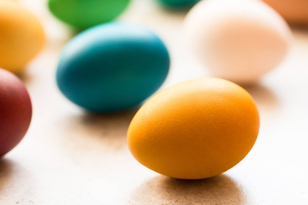 Geel, rood, oranje, blauw en groen paaseieren beschilderd met organische kleurstoffen op een grijze tafel. Traditioneel Pasen. Pasen concept. Minimalisme. Selectieve focus.  - Foto, afbeelding