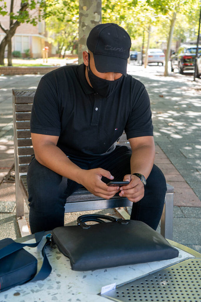 miesmalli poseeraa älykkäässä rento Euroopan muotoinen puku sekä käsilaukku, kannettava tietokone ja avaimet penkillä ja kahvilassa - Valokuva, kuva