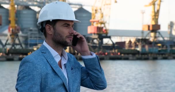 ένας άντρας με προστατευτικό κράνος στο λιμάνι του θαλάσσιου φορτίου μιλάει στο τηλέφωνο, ΗΠΑ - Πλάνα, βίντεο