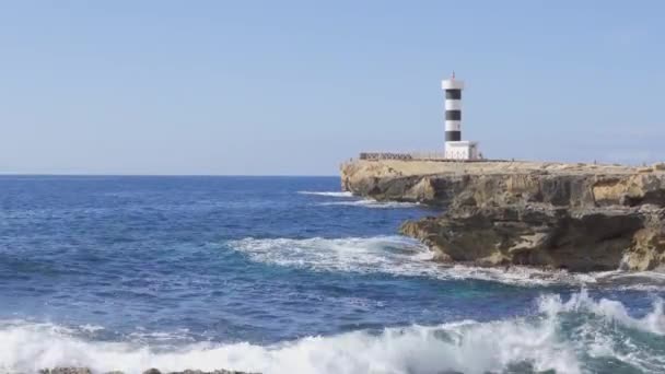Faro de Colonia de Sant Jordi en un día soleado y serpenteante. Mar Mediterráneo en la costa rocosa de la isla de Mallorca, España - Imágenes, Vídeo