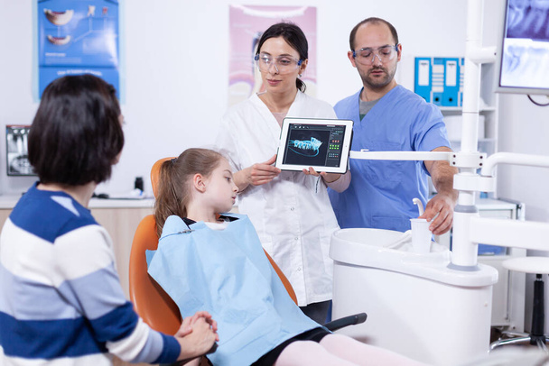 Zahnarzt in Zahnarztpraxis zeigt Tablet-PC mit Kieferröntgenbild - Foto, Bild