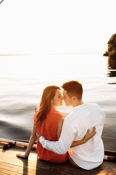 Câlins doux et touchants sur un yacht sur fond d'eau dans la mer, un couple amoureux au coucher du soleil. . Photo de haute qualité - Photo, image