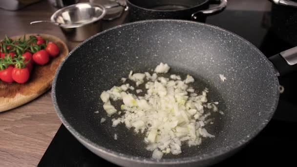 Smažená cibule záběry.close-up nakrájené kousky cibule smažené na pánvi v kuchyni. Smažená cibule na slunečnicovém oleji v pánvi.  - Záběry, video