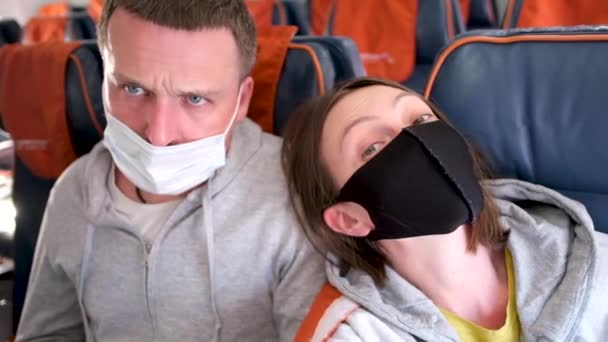 Άντρας και γυναίκα με προστατευτικές μάσκες κάθονται στο αεροπλάνο που τρέμει - Πλάνα, βίντεο