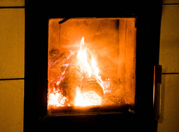 la quema de madera en una chimenea, el brillo y las llamas, la generación de calor en casa - Foto, imagen