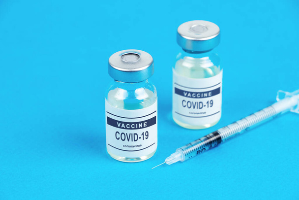 Vaccinatie. Spuit en vaccin COVID-19. Coronavirus op blauwe achtergrond. - Foto, afbeelding
