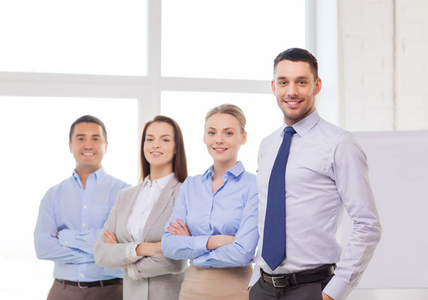 Smiling businessman in office with team on back - Foto, immagini