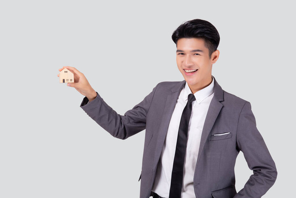 Joven hombre de negocios asiático sosteniendo el símbolo de casa de ahorro para el futuro, agente de seguros y crédito, la propiedad de la casa, la deuda y el préstamo de las finanzas, la compra de la casa y la refinanciación, la inversión inmobiliaria. - Foto, imagen