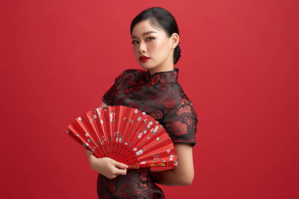 Aasialainen kiinalainen nainen perinteisessä mekossa punaisella taustalla. Kiinalainen uusi vuosi festivaali - Valokuva, kuva