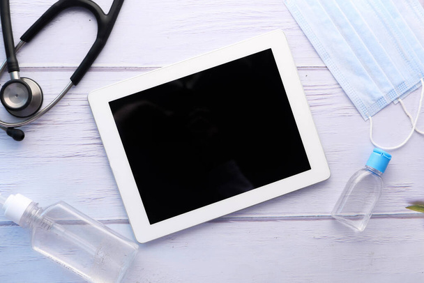 κορυφαία άποψη του ψηφιακού tablet, απολυμαντικό χεριών και στηθοσκόπιο στο τραπέζι  - Φωτογραφία, εικόνα