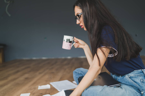 Mujer joven trabajando desde casa sosteniendo una taza de café - Foto, imagen