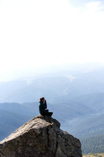 girl meditates in the mountains at sunset sitting in the lotus position - Photo, Image