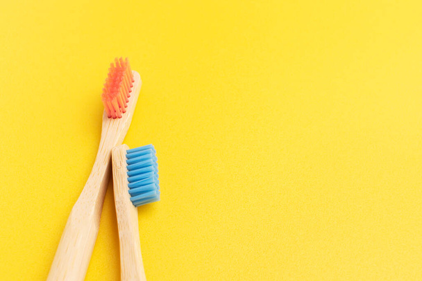 Two bamboo toothbrushes. Eco friendly equipment for personal oral hygiene. Yellow background, top view. - Photo, Image
