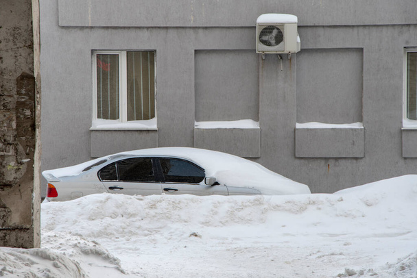 Pysäköidyt autot, lumen peitossa, seisovat tien varrella. Kaupungissa sataa lunta, sataa lumihiutaleita. Konsepti: liikenteen romahtaminen, sademäärän ja lumen lisääntyminen, lumimyrskyt ja lumen ajelehtiminen. - Valokuva, kuva