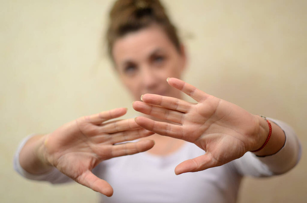 La femme leva les mains devant son visage dans un geste protecteur, éprouvant une émotion négative.  - Photo, image