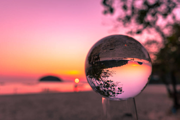 Zonsondergang uitzicht tussen Koh Pu en Kata strand aan de zee kanaal in een kristallen bol, het beeld gezien in de kristallen bol is ondersteboven - Foto, afbeelding