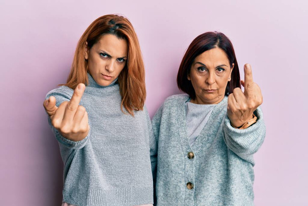Latin mother and daughter wearing casual clothes showing middle finger, impolite and rude fuck off expression  - Photo, Image