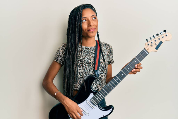 African american woman playing electric guitar smiling looking to the side and staring away thinking.  - Photo, Image