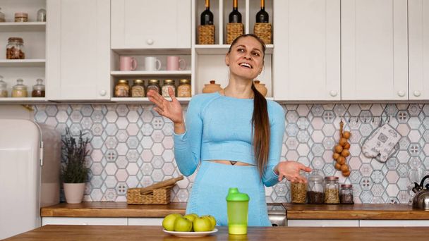 Athletic woman talks about healthy eating in the kitchen and laughs - Fotó, kép