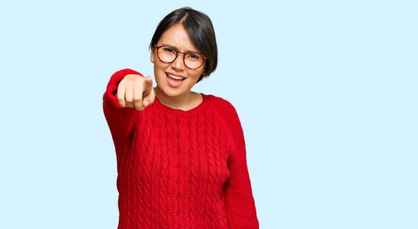 Jonge mooie Latijns-Amerikaanse vrouw met kort haar dragen casual trui en bril wijzen ontevreden en gefrustreerd naar de camera, boos en woedend op u  - Foto, afbeelding