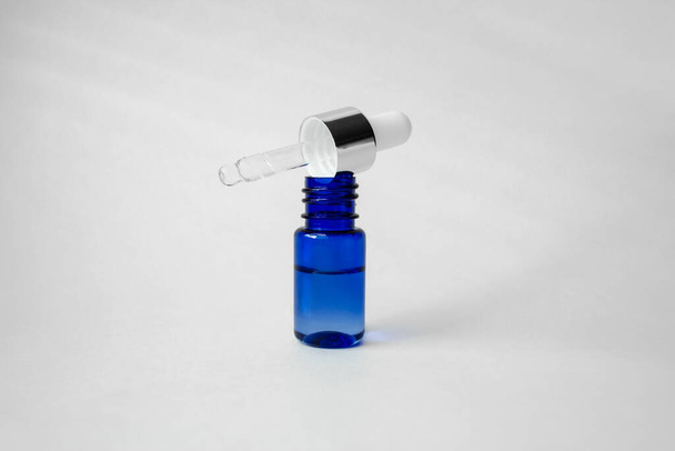 Kék üvegpalack pipetta adagolóval fehér alapon. Kollagén, anti-aging bőrápoló termékek. Bőrhidratáló hialuronsavval. - Fotó, kép
