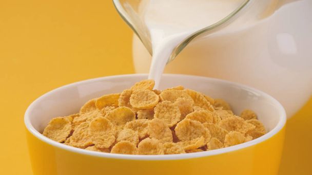 Milch gießt in Schüssel mit Cornflakes - Foto, Bild