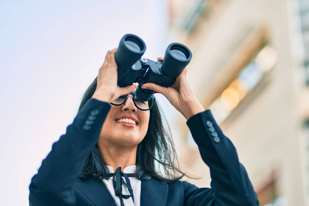 Young hispanic businesswoman looking for new opportunity using binoculars at the city. - Photo, Image