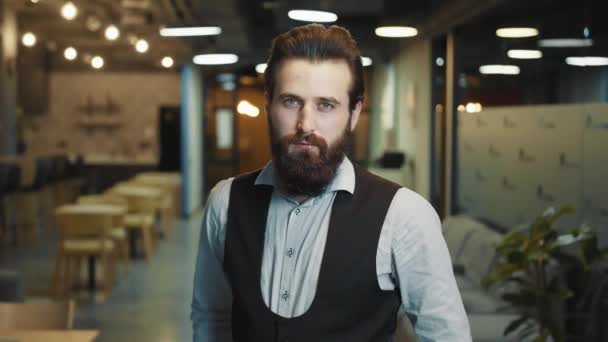 Close up portrait of a successful businessman with a beard of Caucasian appearance. The man folds his arms and looks intently at the camera. The look of a confident businessman leader. - Footage, Video